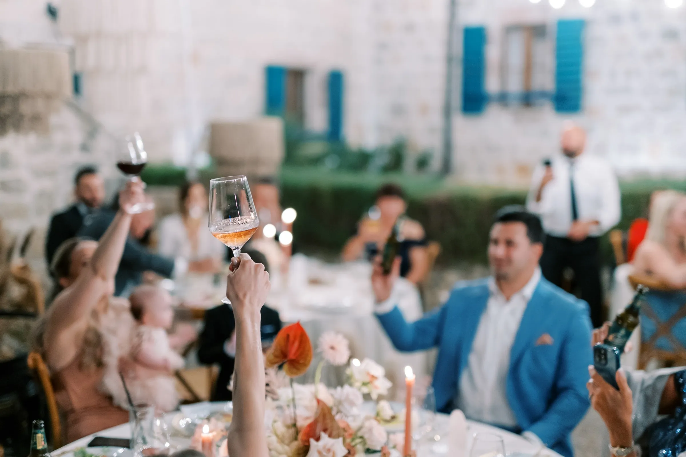 Wedding guests raising their glasses in a toast at an outdoor reception