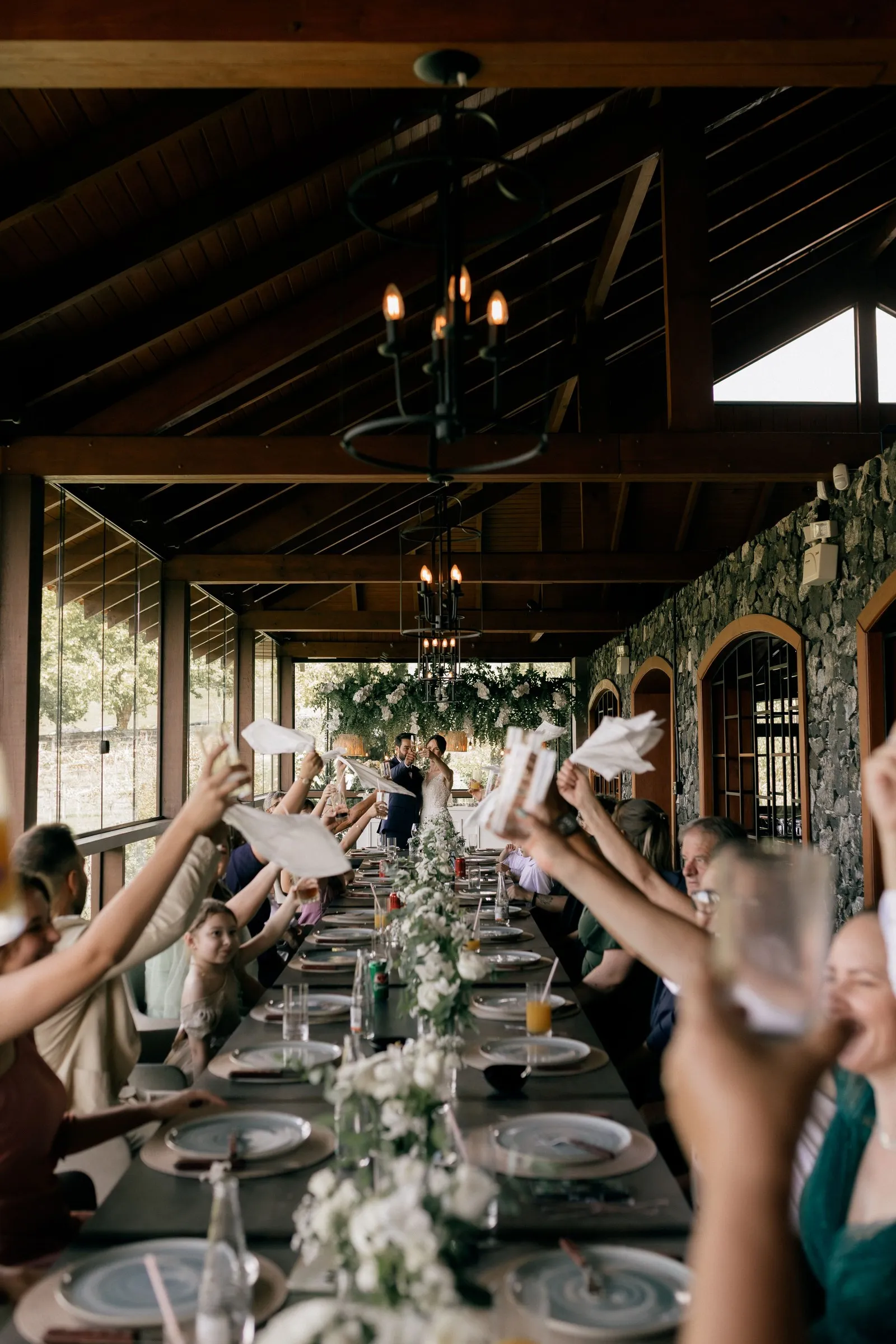 Black-and-white photo of guests waving napkins along a long banquet table